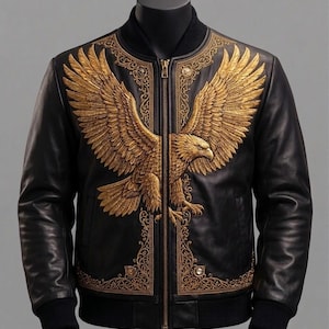 May include: A black leather bomber jacket featuring a large, detailed gold-colored eagle emblem across the chest. The design includes intricate gold filigree patterns along the front panels and a central gold-toned zipper closure with ribbed cuffs.