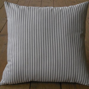 May include: A white cushion with thin grey stripes. The cushion is square and has a soft, textured fabric.