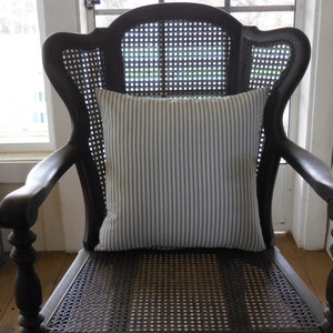 May include: A black wooden chair with a cane back and seat. The chair has a white and blue striped cushion on the seat.