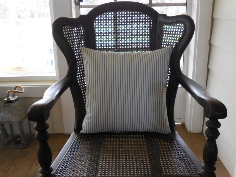 May include: A black wooden chair with a cane back and seat. The chair has a white and blue striped cushion on the seat.