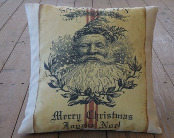 May include: A cream-colored pillow with a vintage-style illustration of Santa Claus with a red and white striped background. The text "Merry Christmas Joyeux Noel" is printed below the image.