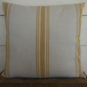 May include: A white pillow with yellow stripes. The pillow is made of a soft, textured fabric.