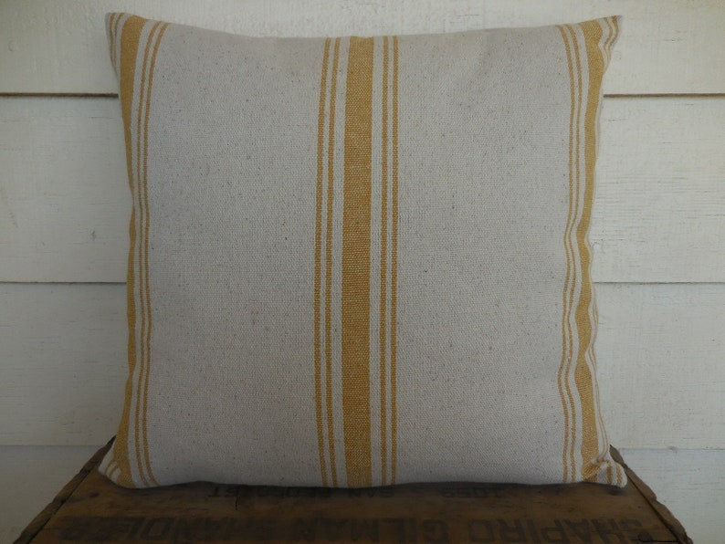 May include: A white pillow with yellow stripes. The pillow is made of a soft, textured fabric.