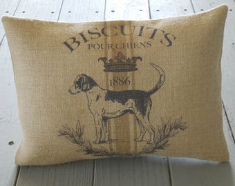 May include: A brown burlap pillow with a black and white illustration of a dog and the text "Biscuits Pour Chiens 1886".
