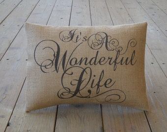 May include: A brown burlap pillow with the text "It's a Wonderful Life" printed in black cursive font.