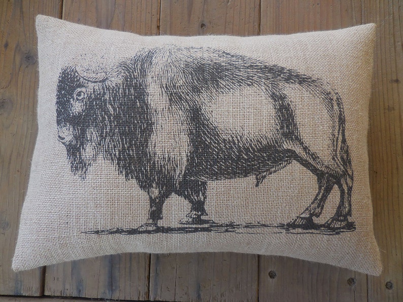 May include: A brown burlap pillow with a black and white illustration of a bison.