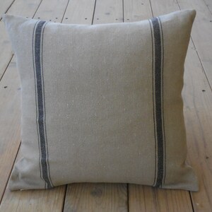 May include: A beige linen pillow with black stripes. The pillow is made of a soft, natural fabric and has a simple, elegant design.