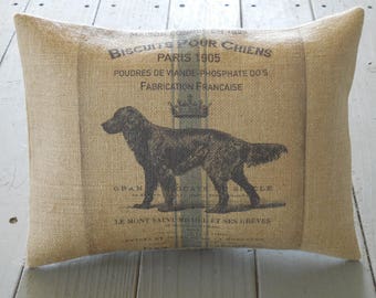 May include: A burlap pillow with a vintage design featuring a black and white illustration of a dog and the text "Biscuits Pour Chiens Paris 1905 Poudres de Viande Phosphate Do's Fabrication Française".