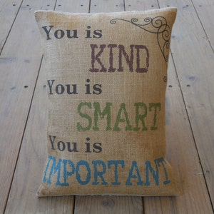 May include: A burlap pillow with the text "You is KIND, You is SMART, You is IMPORTANT" printed in different colors.