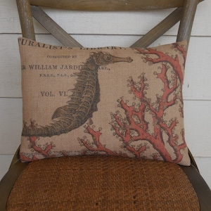 K&ouml;nnte beinhalten: Ein beigefarbenes Kissen aus Jute mit einem roten Korallen- und Seepferdchen-Design. Das Kissen zeigt eine Vintage-Illustration eines Seepferdchens und Korallen mit dem Text "Naturalist's Library Conducted by Sir William Jardine, F.R.S.E., F.L.S., &c. Vol. VI."