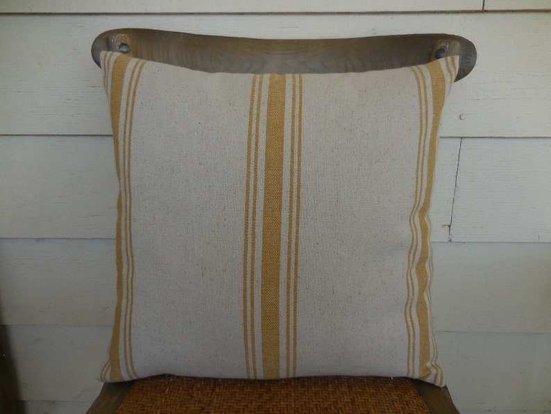 May include: A beige and mustard yellow striped throw pillow with a subtle linen texture.