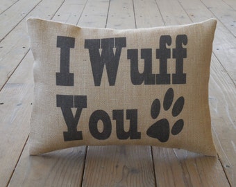 May include: A brown burlap pillow with the text "I Wuff You" in black block letters and a black paw print.