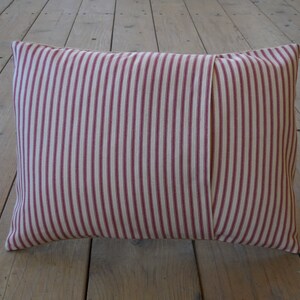 May include: A red and white striped pillow with a seam down the center.