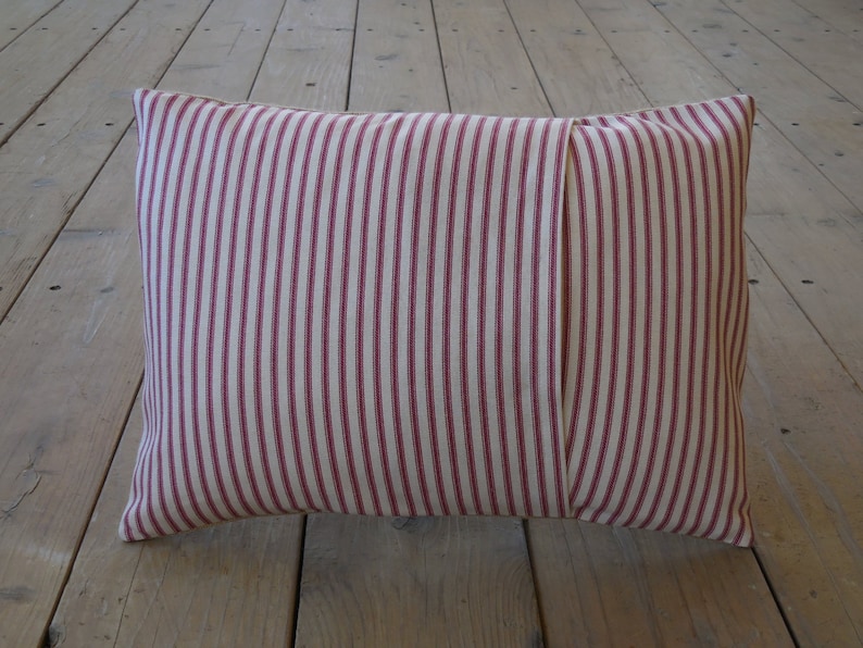 May include: A red and white striped pillow with a seam down the center.