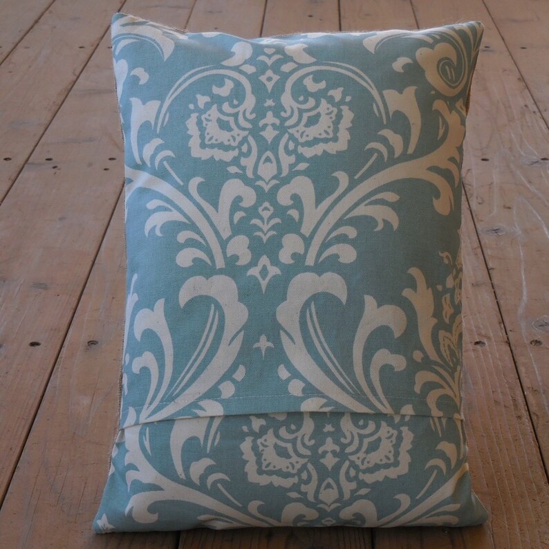 May include: A blue and white patterned pillow with a damask design. The pillow has a hidden zipper closure on the back.