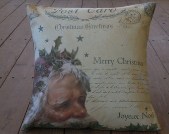 May include: A cream-colored pillow with a vintage Christmas postcard design. The postcard features a Santa Claus illustration with holly and the text "Post Card", "Christmas Greetings", "Merry Christmas", and "Joyeux Noel".