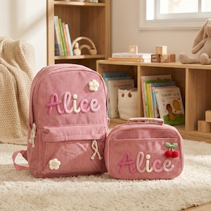 May include: Pink corduroy backpack and matching lunch bag set. The backpack and lunch bag are personalized with the name "Alice" in a decorative font. The backpack has a front pocket and flower accents.