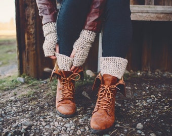 May include: A pair of brown leather boots with laces, worn with white crocheted leg warmers and a brown leather jacket.