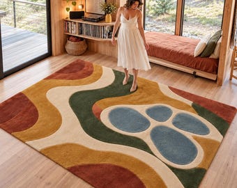 May include: A rectangular area rug featuring a wavy, abstract pattern in shades of terracotta, mustard yellow, forest green, cream, and slate blue. The design consists of flowing, organic shapes and rounded, pebble-like forms across the surface.