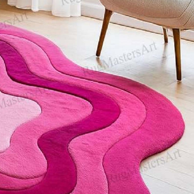 Contemporary pink tufted rug with flowing ripple pattern, irregular shaped abstract carpet, soft modern area rug for chic living room, cute dorm decor and feminine aesthetic spaces.