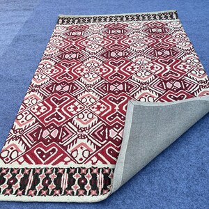 Handmade wool rug with red cream and black repeating geometric motifs