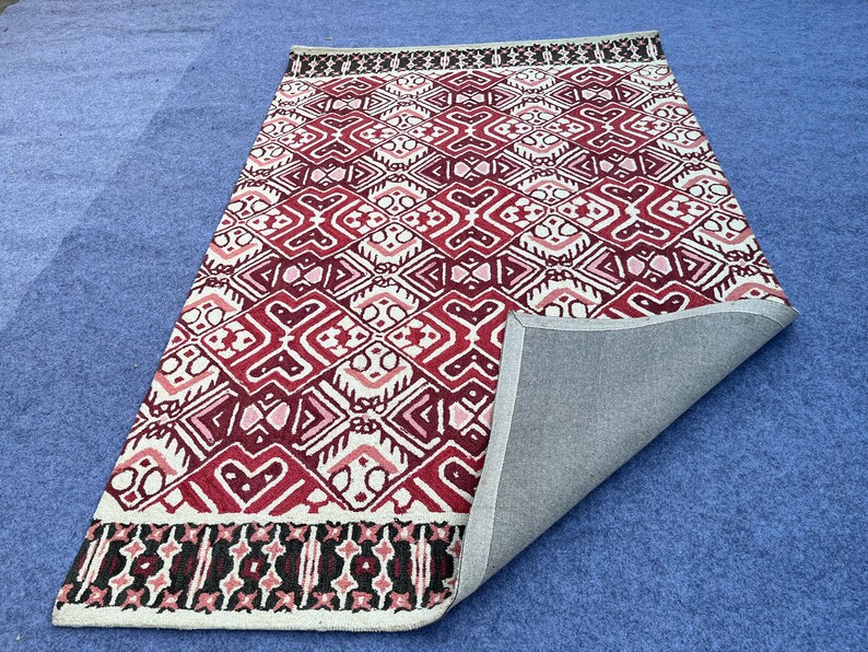 Handmade wool rug with red cream and black repeating geometric motifs