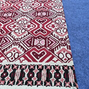 Hand tufted red area rug with bold geometric motifs and decorative border