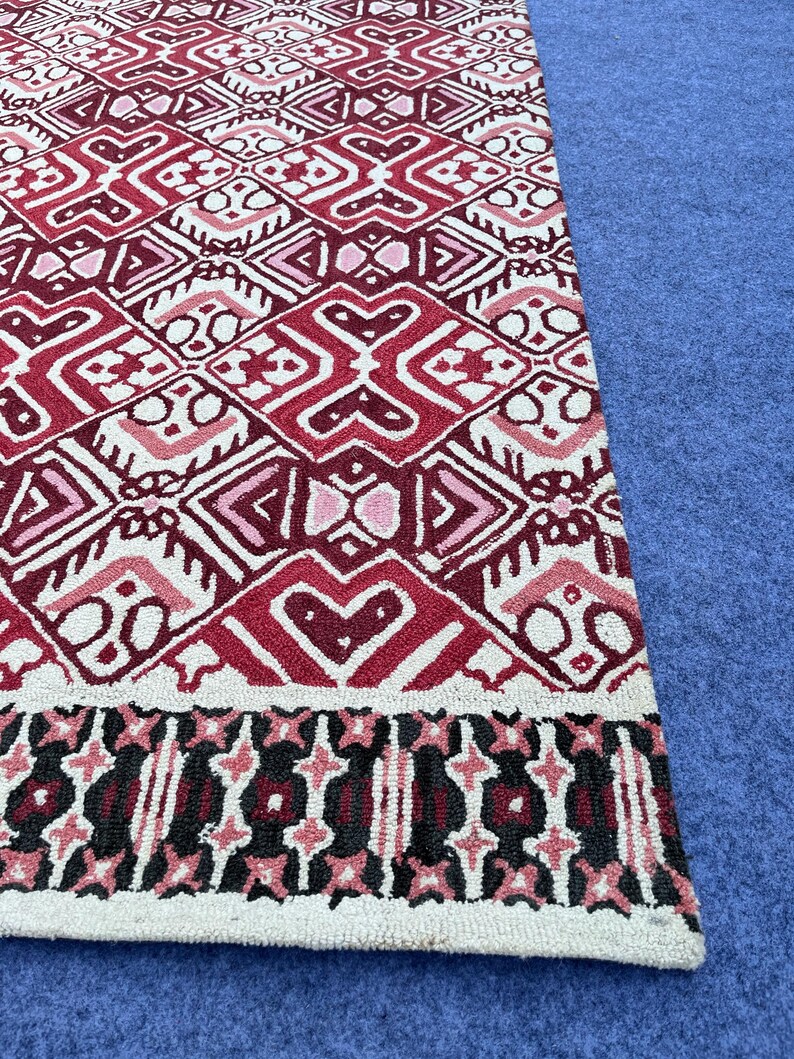 Hand tufted red area rug with bold geometric motifs and decorative border