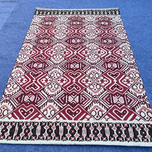 Burgundy wool area rug with detailed geometric pattern and contrasting cream motifs