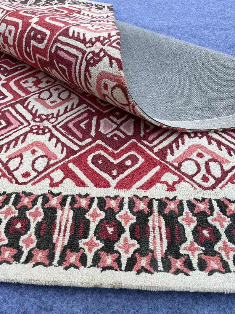 Statement living room rug with burgundy geometric pattern and dark decorative border