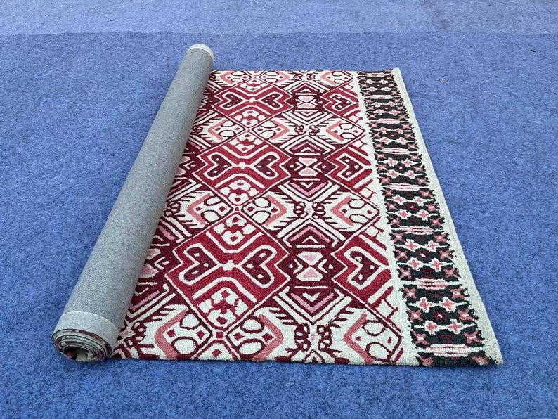 Hand tufted wool carpet with burgundy geometric motifs and cream detailing