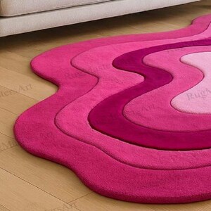 Close-up of hand tufted pink wave rug with irregular organic shape, modern abstract contour carpet, fluffy layered area rug for chic bedroom, trendy living room and feminine home decor.