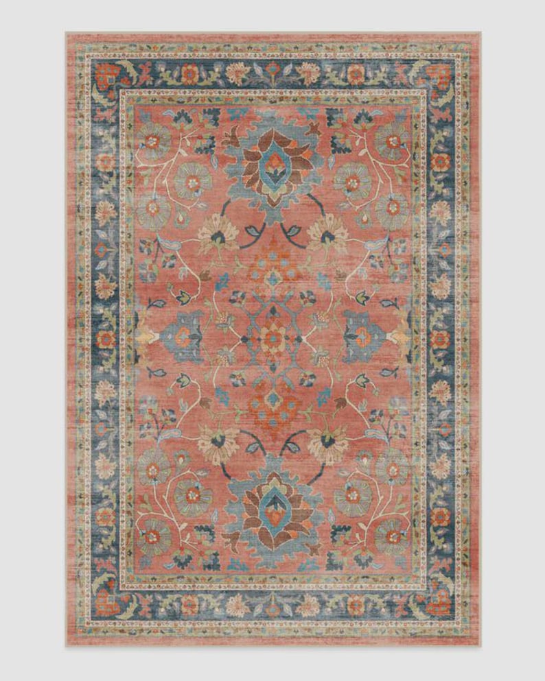 Pu&ograve; includere: Tappeto rettangolare con motivo floreale nei toni del corallo, blu e beige. Il tappeto presenta un design a medaglione centrale e un bordo con intricati motivi floreali. La palette di colori e il design del tappeto creano un'estetica vintage.