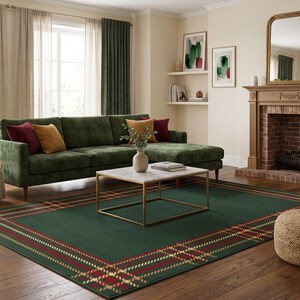 May include: A rectangular area rug featuring a deep green base with a prominent plaid border pattern in red, gold, and white lines. The rug is positioned on a wooden floor in a living room setting, centered beneath a white marble coffee table.