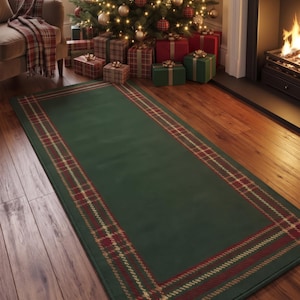 May include: A rectangular area rug featuring a solid dark green center bordered by a classic red, gold, and dark green plaid pattern. The rug has a finished edge and is positioned on a wooden floor, showcasing a traditional textile design.