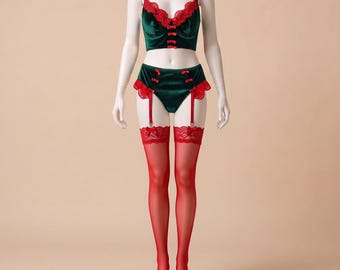 May include: A dark green velvet lingerie set featuring a bustier top and high-waisted briefs with red lace trim and small red bows. The set includes matching red sheer thigh-high stockings attached to the briefs with red garter straps.