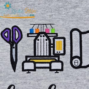 May include: Embroidered design on a gray fabric featuring sewing tools and a machine. The design includes a spool of thread, purple scissors, a sewing machine with colorful thread spools, and a roll of fabric.