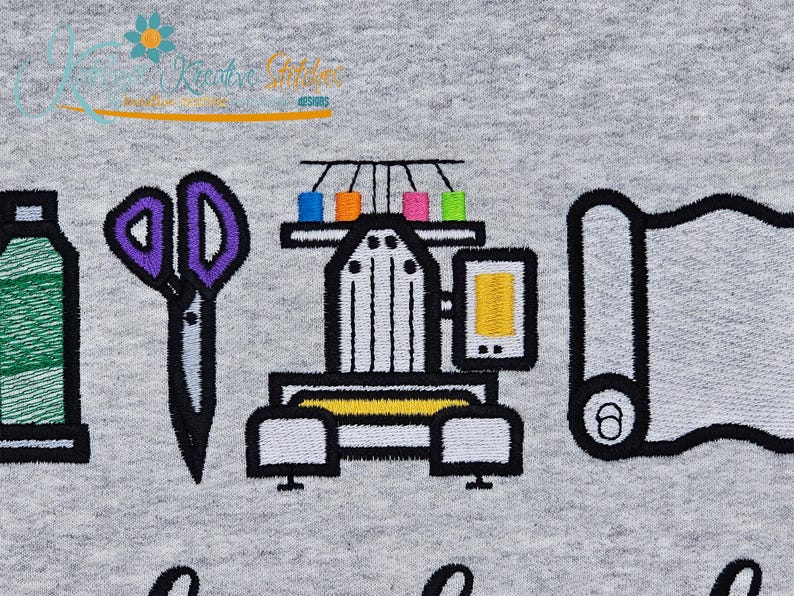 May include: Embroidered design on a gray fabric featuring sewing tools and a machine. The design includes a spool of thread, purple scissors, a sewing machine with colorful thread spools, and a roll of fabric.