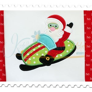 May include: Embroidered design of Santa Claus riding a green and red snowmobile with white polka dots. The snowmobile has a blue windshield and black skis. Santa is wearing a red suit, white beard, and black boots.