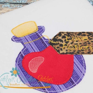 Puede incluir: Una botella de vidrio púrpura con una tapa amarilla y un corazón rojo en su interior. La botella tiene una etiqueta adjunta que dice "Love Potion" en letras doradas sobre un fondo de estampado de leopardo marrón.
