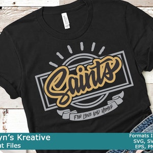 以下が含まれることがあります： 黒地に金とグレーのグラフィックデザインが施されたTシャツで、「Saints」の文字と、その下に「For Love and Honor」の文字が書かれたバナーがあります。