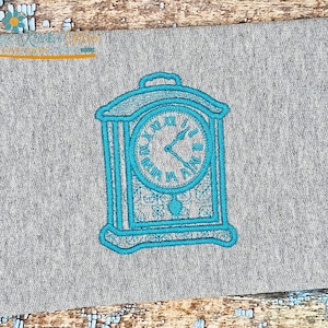 May include: A teal embroidered clock design on grey fabric. The clock face has Roman numerals and decorative detailing. The design is centred on the fabric, showcasing a vintage aesthetic.