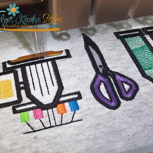 May include: Embroidered design featuring a sewing machine, scissors, and colorful thread spools. The sewing machine has a yellow square and a brown top. The scissors are purple and gray. The text "Katelyn's Kreative Stitches" is in the upper left corner.