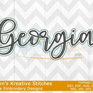May include: Machine embroidery design of the word "Georgia" in a cursive font with a black outline and a teal inner shadow.