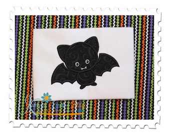 Puede incluir: Un diseño bordado en blanco y negro de un murciélago con una cara linda sobre un fondo de tela blanca. La tela está rodeada por un borde de rayas de colores.