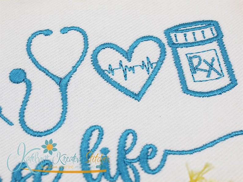 May include: Embroidered design featuring a stethoscope, a heart with a heartbeat line, and a pill bottle with an RX symbol. The text "a life" is also embroidered in blue thread.