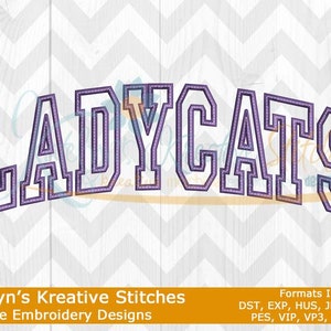 May include: Machine embroidery design of the word "LADYCATS" in a purple and white color scheme. The design is outlined in black and has a stitched effect. The text "Katelyn's Kreative Stitches Machine Embroidery Designs" and "Formats Included: DST, EXP, HUS, JEF, JEF+, PES, VIP, VP3, and XXX" are also included in the image.