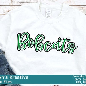 Peut inclure: Un sweat-shirt blanc avec le mot "Bobcats" écrit en lettres vertes et noires. Le texte est souligné en noir et rempli de vert.