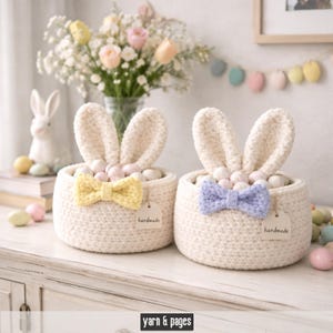 Könnte beinhalten: Zwei cremefarbene Häschenkörbe aus Häkelarbeit mit großen Ohren und Schleifen. Einer hat eine gelbe Schleife, der andere eine hellviolette Schleife. Jeder Korb hat ein "handmade"-Etikett und ist mit Ostereiern gefüllt.