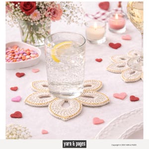 Può includere: Un bicchiere d'acqua con limone poggia su un sottobicchiere all'uncinetto a forma di fiore, color crema e bordato d'oro. Decorazioni a forma di cuore e candele sparse.